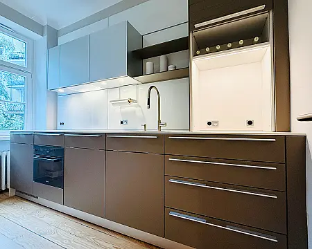 bulthaup Serie b3 mit Fronten in Laminat lehm / Oberschränke in alu natur / Paneele in glas weiß · "elegante Küchenzeile mit hochwertiger Ausstattung und kostbaren Materialen bzw. Details"