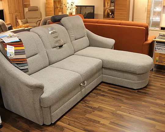 Schlichte hellgraue Couch verbirgt praktische Funktionen und kommt zusammen mit passendem Sessel auf Rollen - Systemgarnitur
