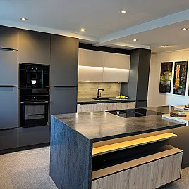 Moderne, elegante Einbauküche mit Wandzeile, Kochinsel, Baransatz und rückwertigem Sideboard, sowie Arbeitsplatte aus Corian-Mineralwerkstoff