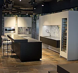 Edelstahl-Küche mit Möbeln in hellgrau-matt und Wave-Optik in schwarz