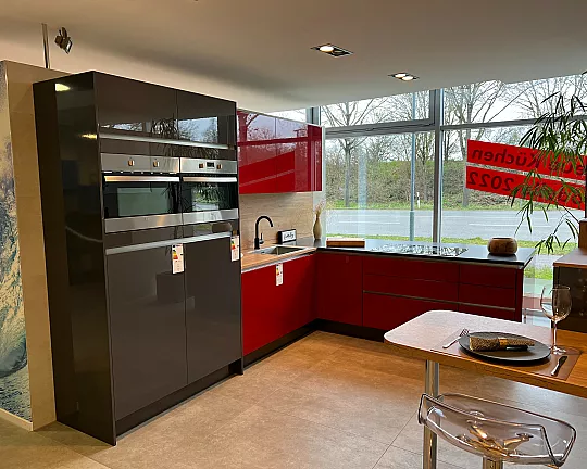 Moderne, grifflose L-Küche mit Sitzgelegenheit, Ansatztisch und Sideboard - Laser Brillant in chilirot und graphit