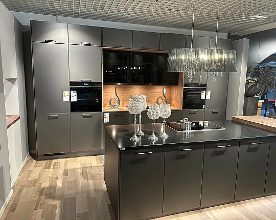 Glas-Optik in Titano Matt, abgesetzt in Eiche und eine Arbeitsplatte aus Quarzstein Epic Black - Großzügige Inselplaung mit Hochschrankzeile und Quarzarbeitsplatte