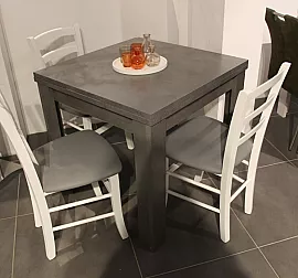 Grauer kleiner Esstisch und weiße Stühle bilden modernen Kontrast