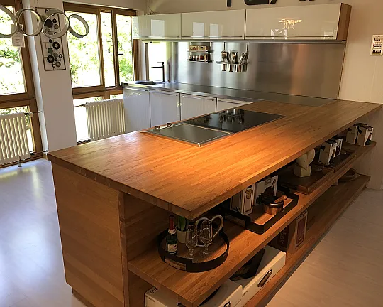 Naturholz trifft Glas. Schöne Küche mit Edelstahlarbeitsplatte, hochgebautem Backofen und Kochinsel - Weißglas/Eiche