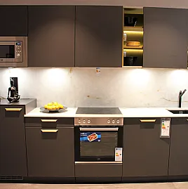 Einzelne Küchenzeile in modernem Lavaschwarz mit messingfarbenen Griffen & olivgelbem Regal als Farbtupfer