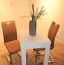Kleiner weißer ausziehbarer Esstisch mit farbenfrohen Schwingstühlen