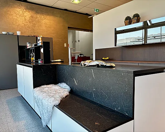 Designküche mit riesiger Insel in der ein raffinierter Sitzplatz eingearbeitet ist. Die Farbkombi aus steinweiß, balsaltgrau und dem kräftigen arabica oak besticht durch ihre zeitlosigkeit. Geräte von Bora, Miele und Liebherr. - Sentu GL 09 - AM steinweiß und AM basaltgrau / Finiso GL 03 - arabica oak