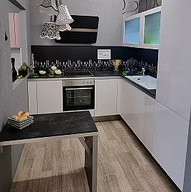 Moderne grifflose Küche mit weißer Lackfront und eleganter Nischenverkleidung in kontrastreichem Schwarz