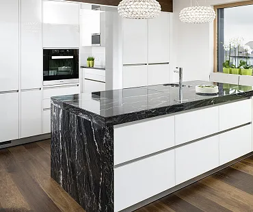 Weiße Küche mit schwarzer Natursteinarbeitsplatte