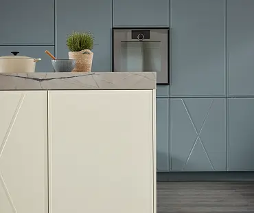 Eleganter Farbkontrast zwischen cremeweißer Insel und blaugrauer Küchenzeile